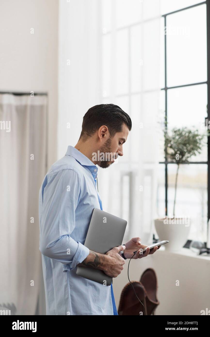 Businessman using phone while standing in office Stock Photo
