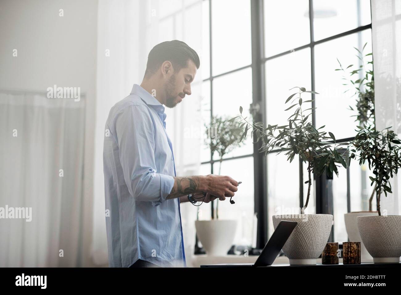 Businessman using laptop while standing at table in office Stock Photo