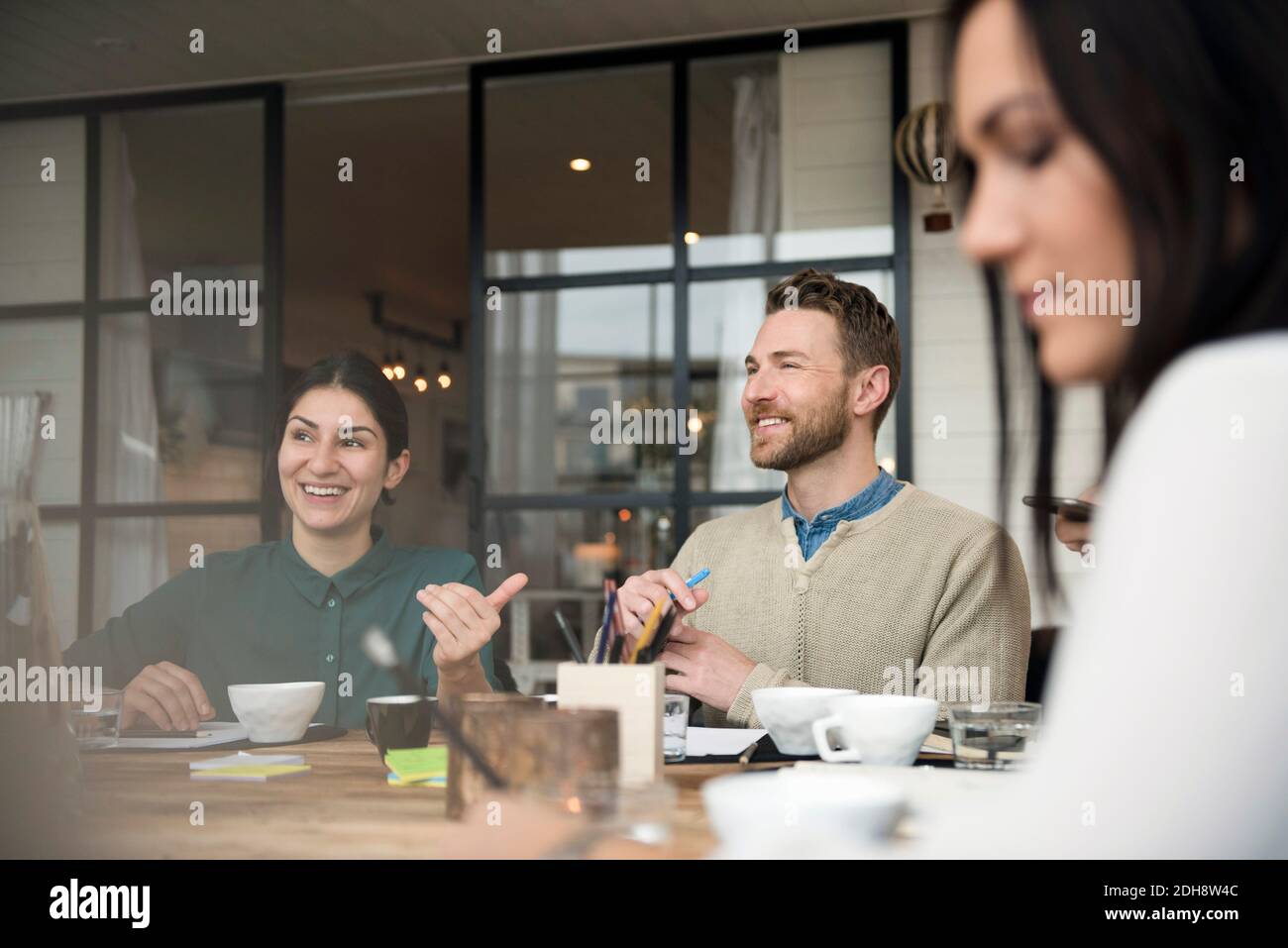 Happy business people talking while having coffee at table during meeting in office Stock Photo