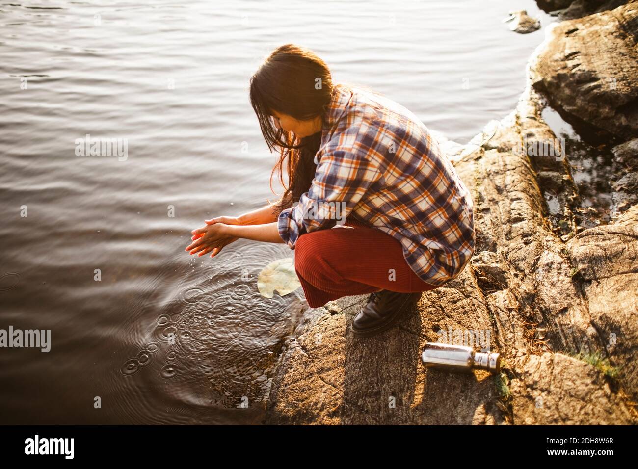 High angle view of woman washing hands by lake in forest Stock Photo