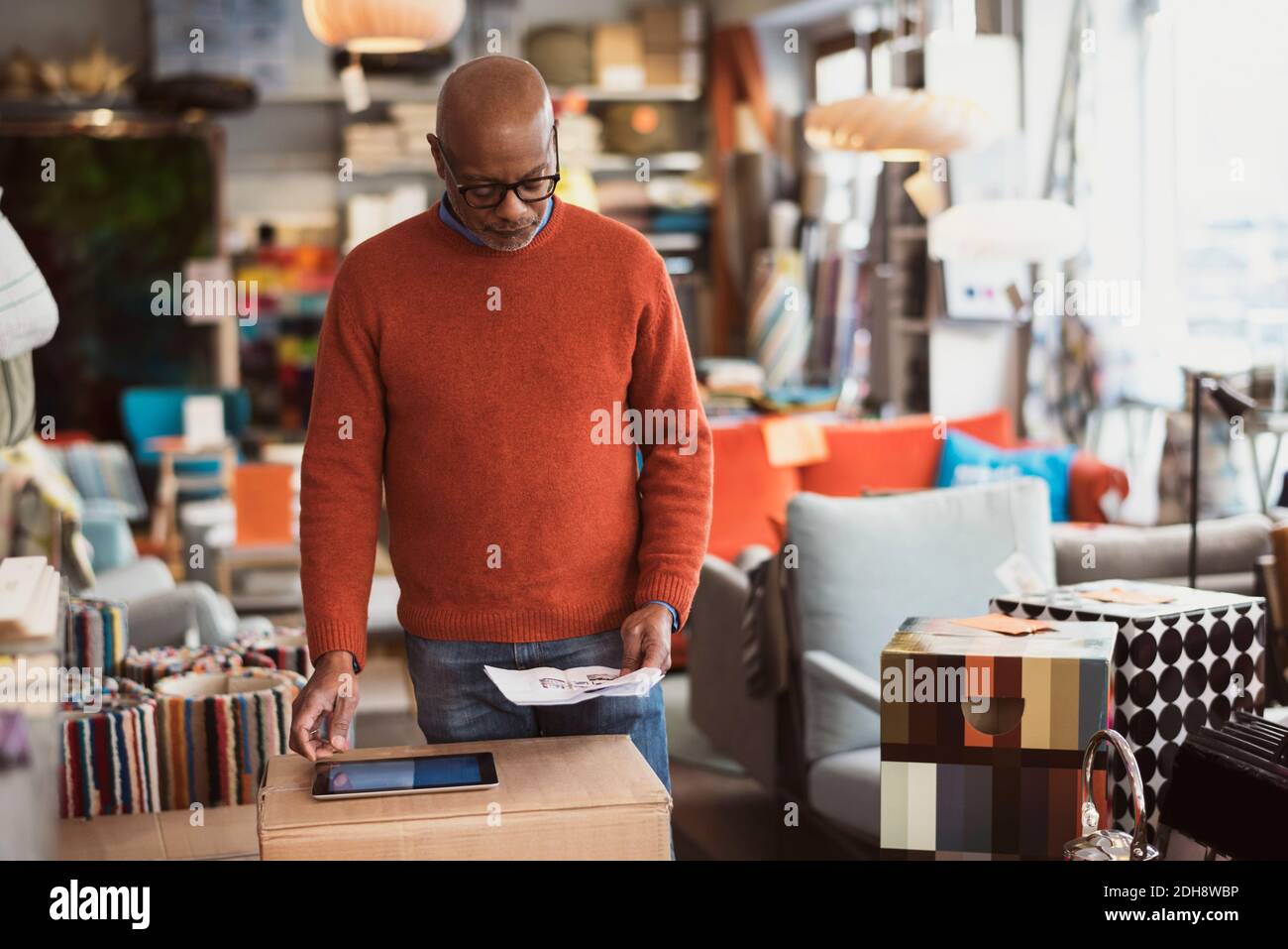 Senior man using digital tablet while reading document at store Stock Photo