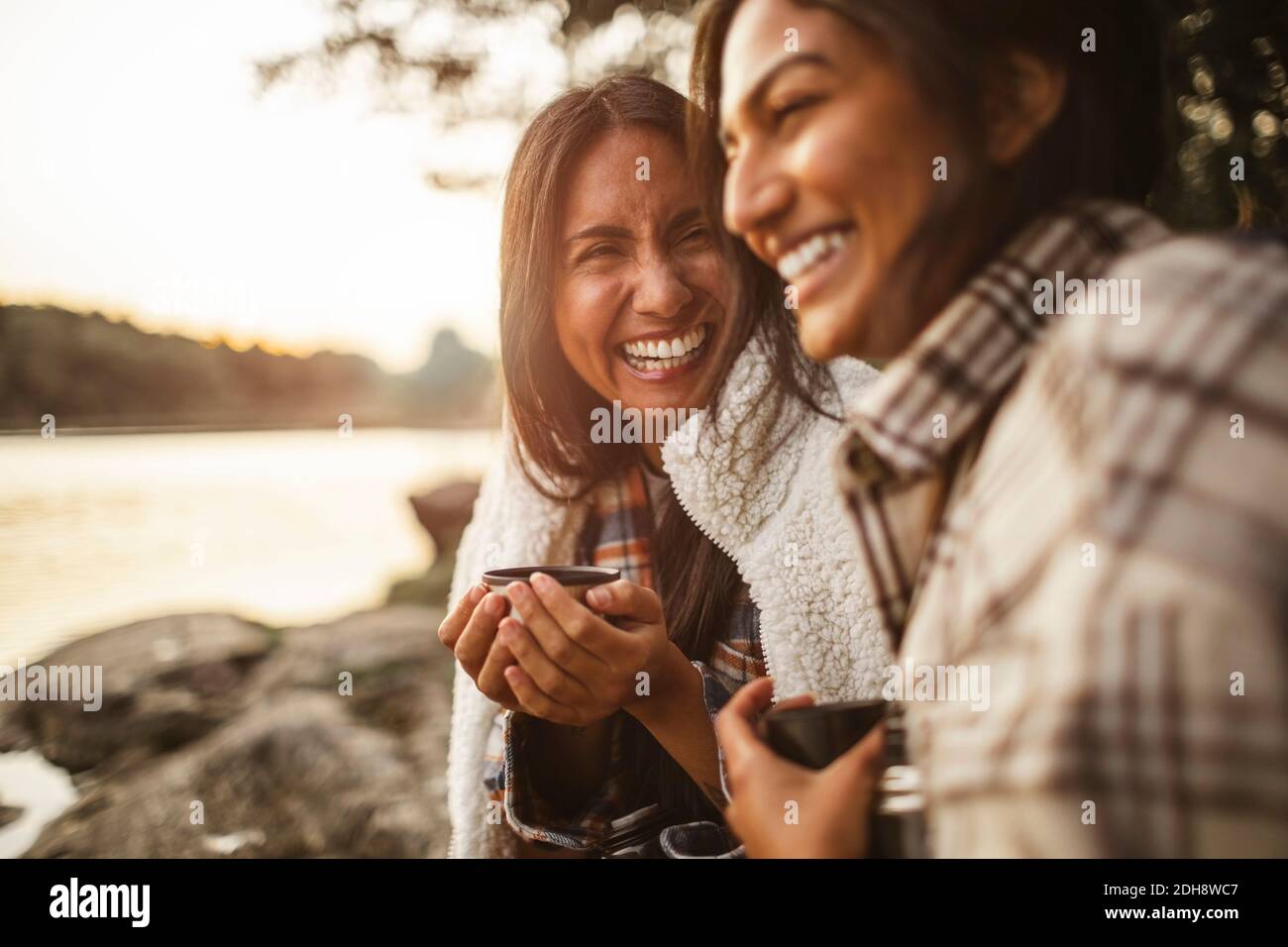 Cheerful female friends talking while drinking coffee in forest Stock Photo