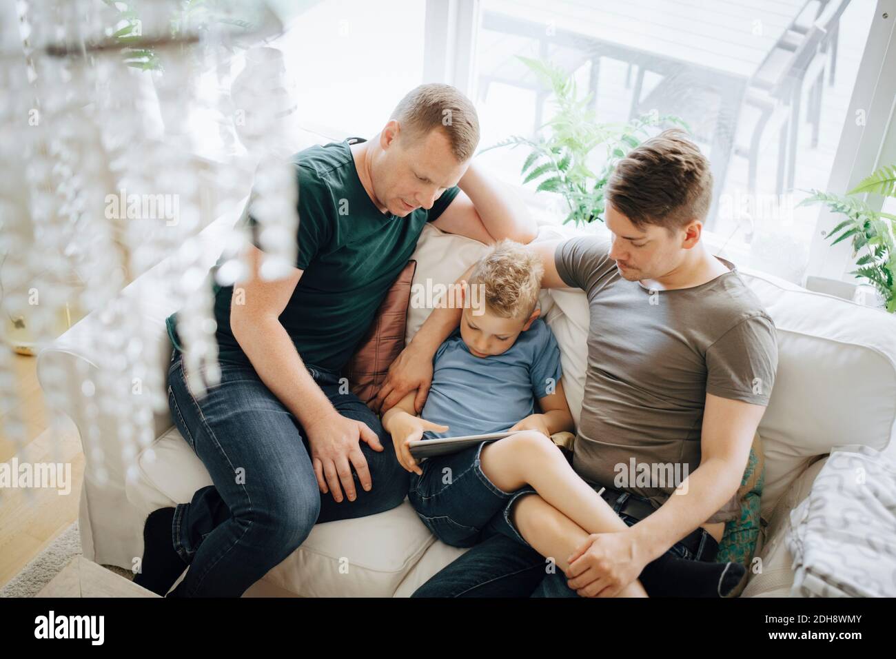 High angle view of homosexual fathers sitting while son using digital tablet at home Stock Photo