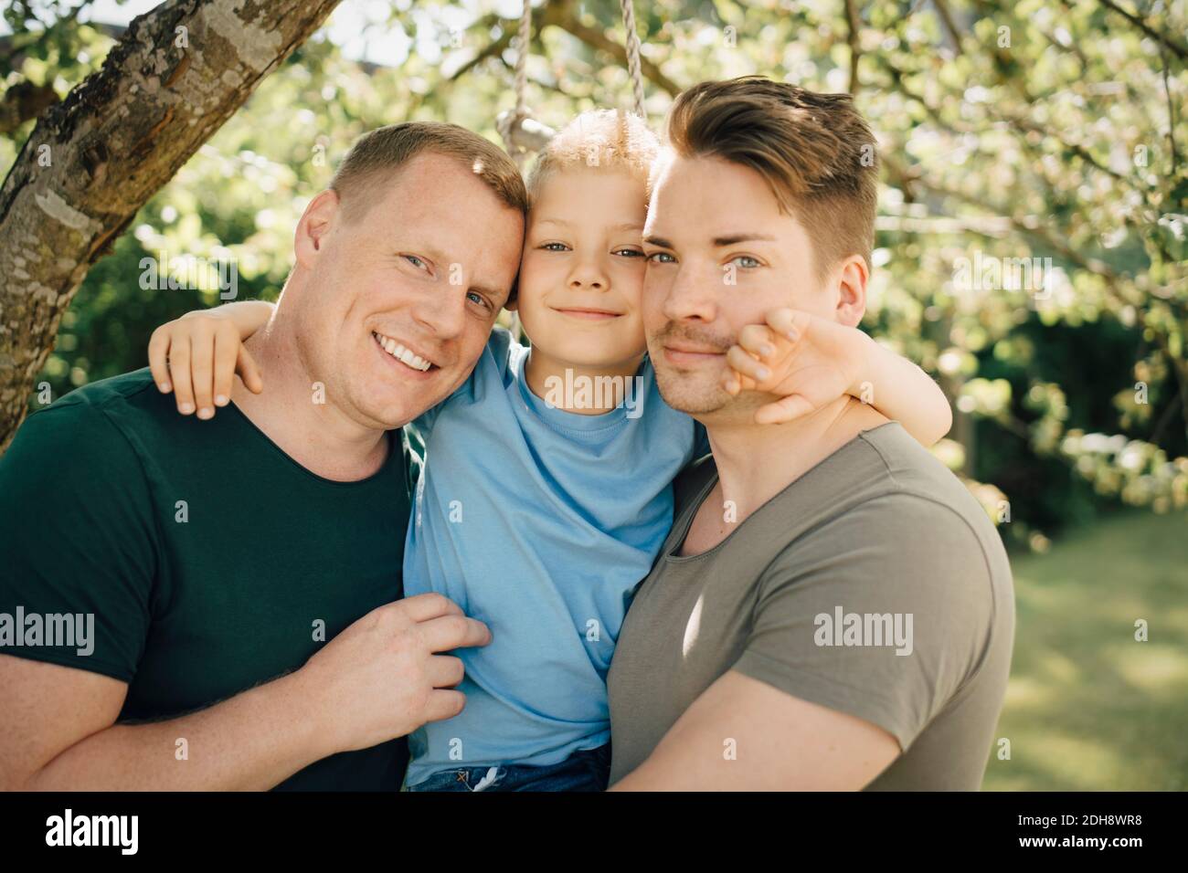 Portrait of homosexual fathers with son standing in yard Stock Photo