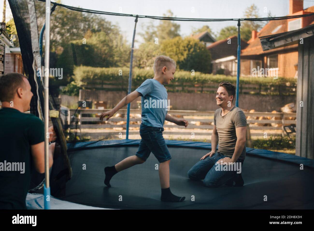 Smiling father and son playing in trampoline during weekend Stock Photo