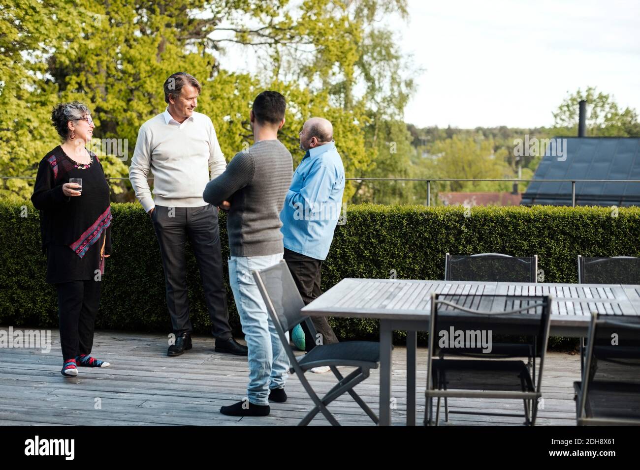 Multi-ethnic friends talking while standing by table in yard Stock Photo