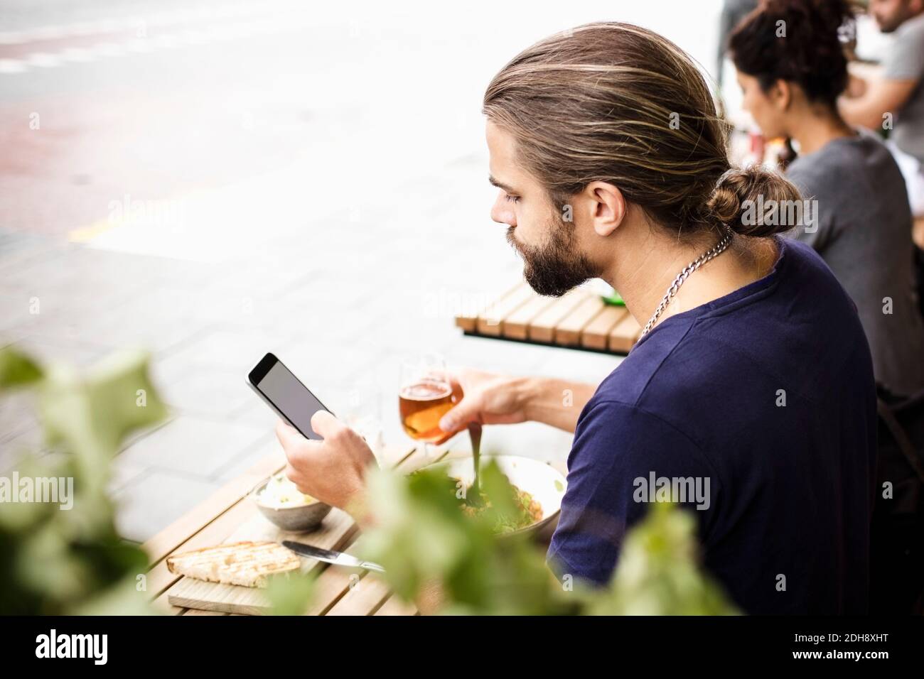 Man using mobile phone while having drink at sidewalk cafe Stock Photo