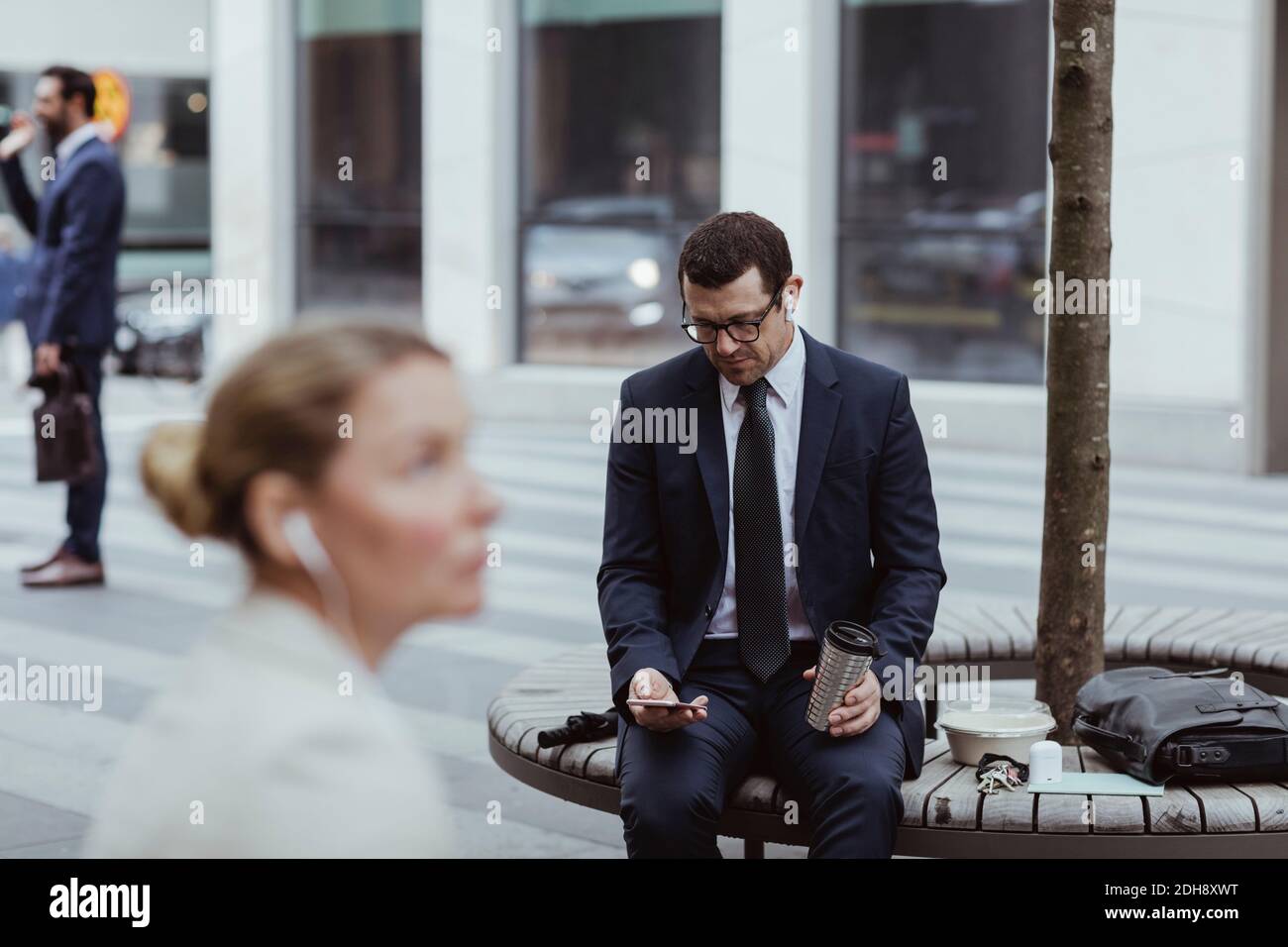 Entrepreneur using mobile phone while sitting in city Stock Photo