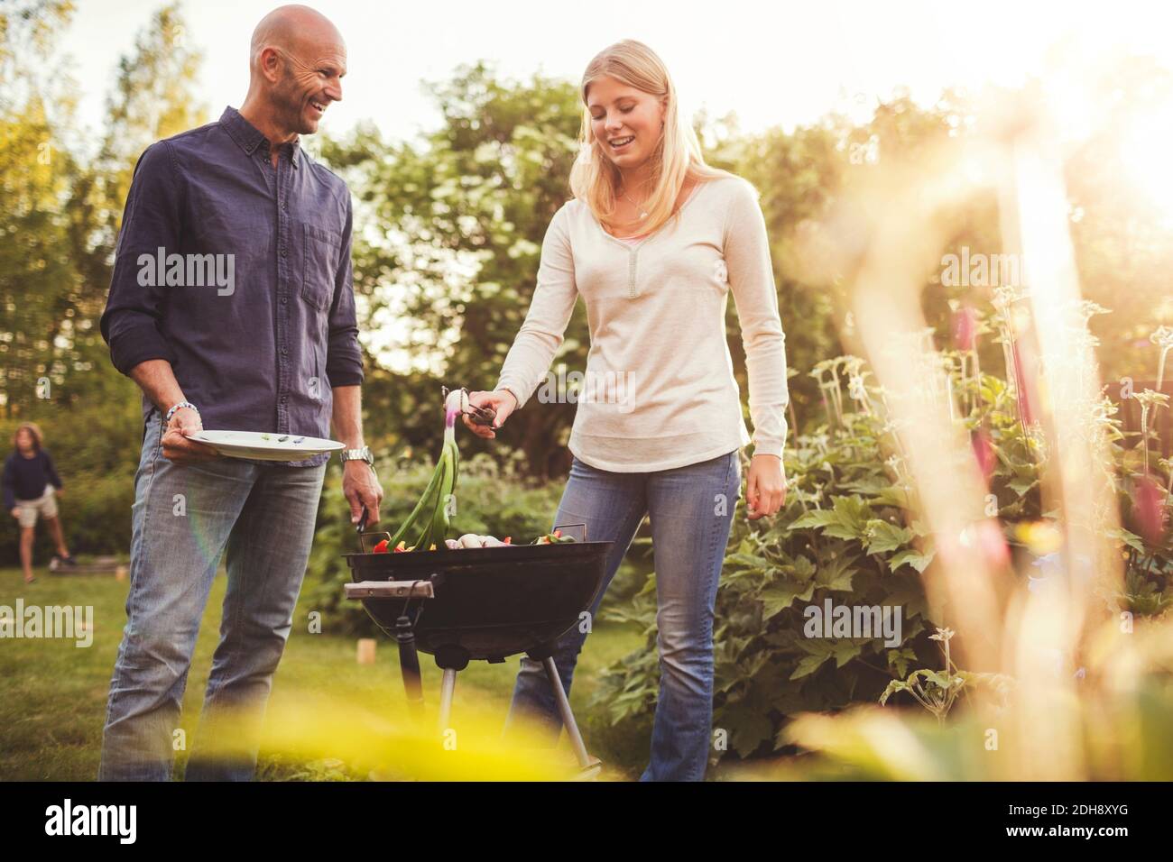 Happy father and daughter cooking vegetables on barbecue grill in back yard Stock Photo
