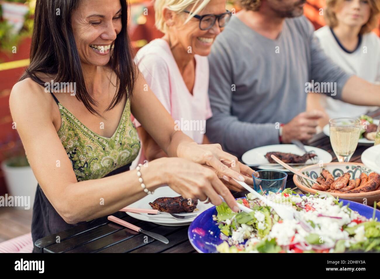 Happy people sitting at dining table during garden party in back yard Stock Photo