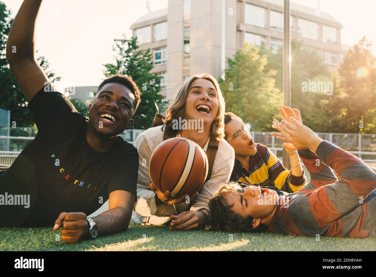 Happy friends cheering while lying down in park Stock Photo