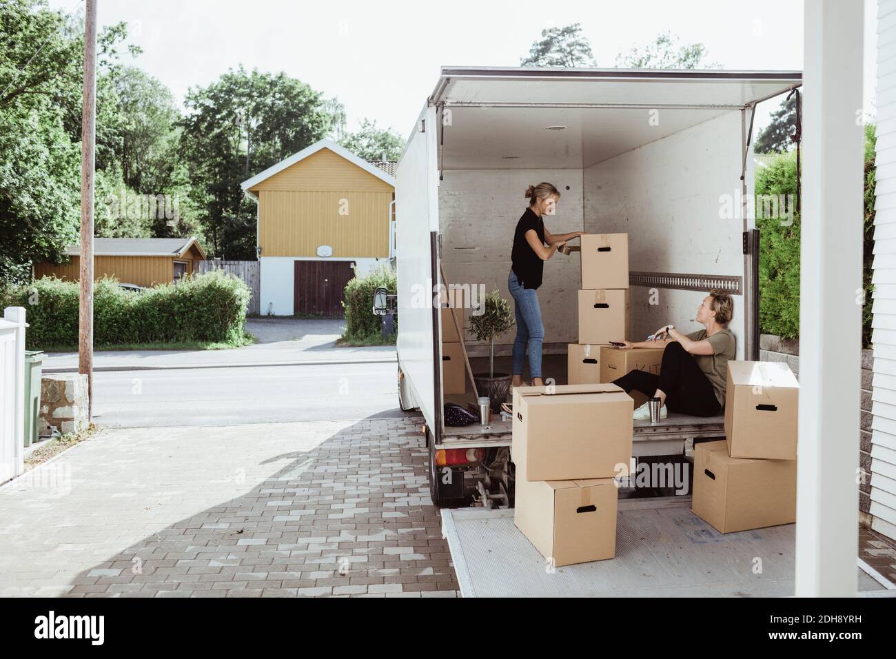 Side view of woman with boxes talking to female friend in moving van Stock Photo