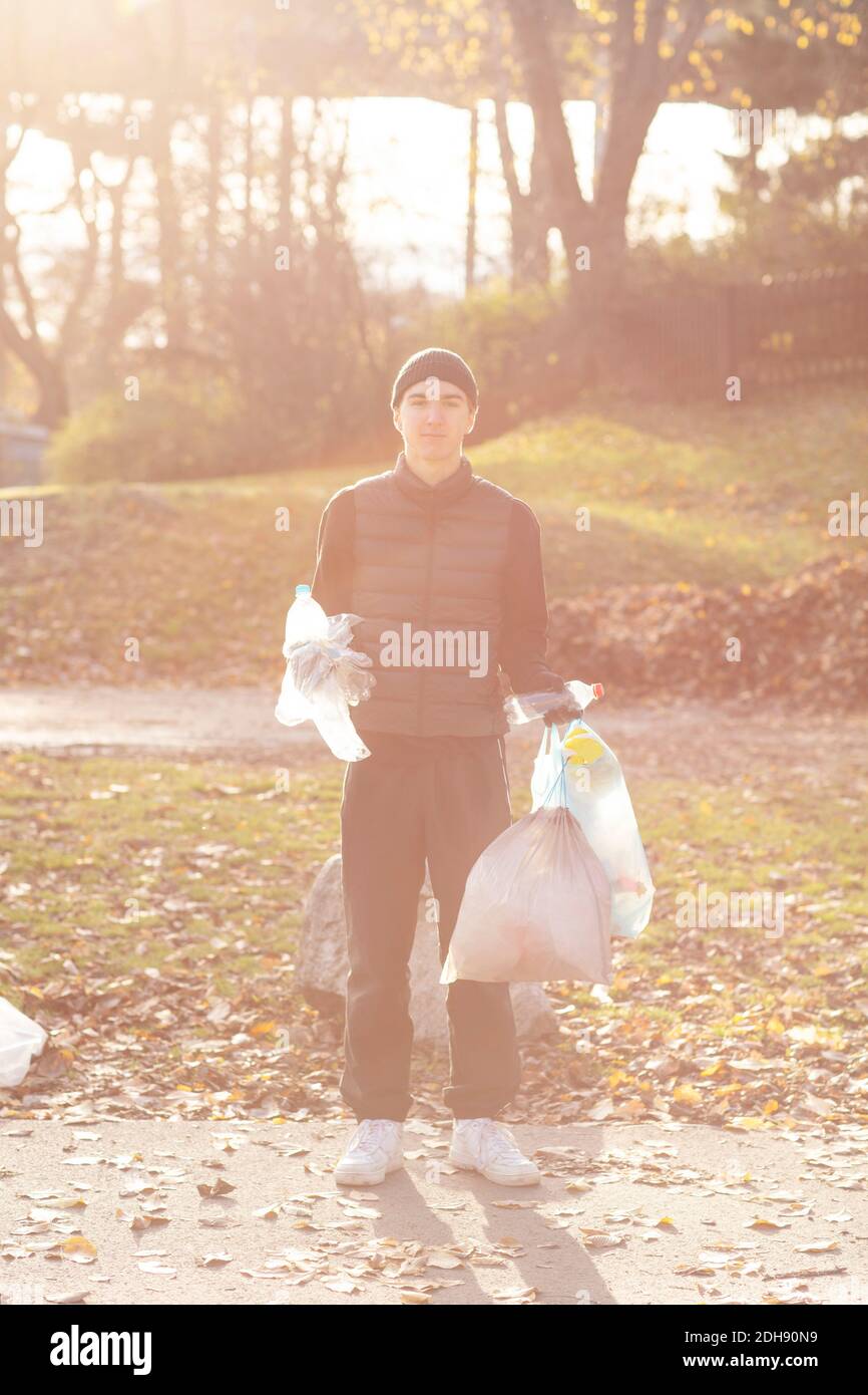 Portrait of young male volunteer with plastic garbage standing in public park Stock Photo