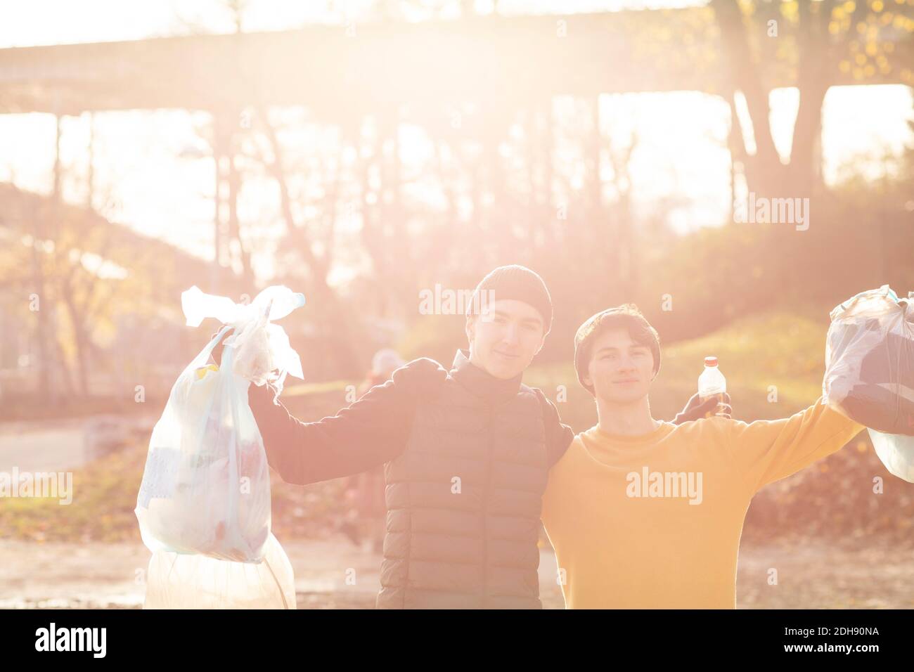 Portrait of young male volunteers with plastic garbage standing in public park Stock Photo