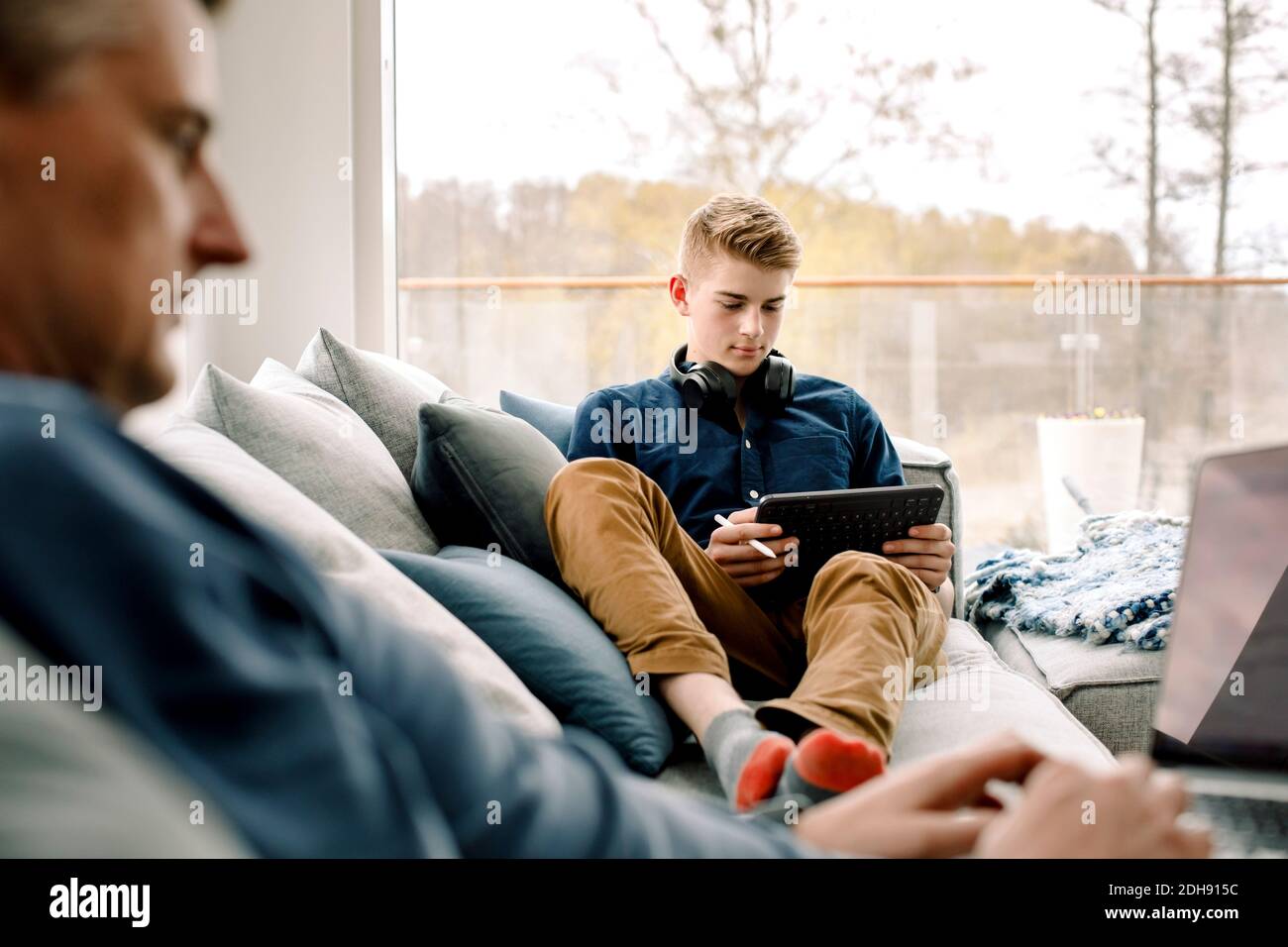 Teenage boy using digital tablet on sofa at home Stock Photo