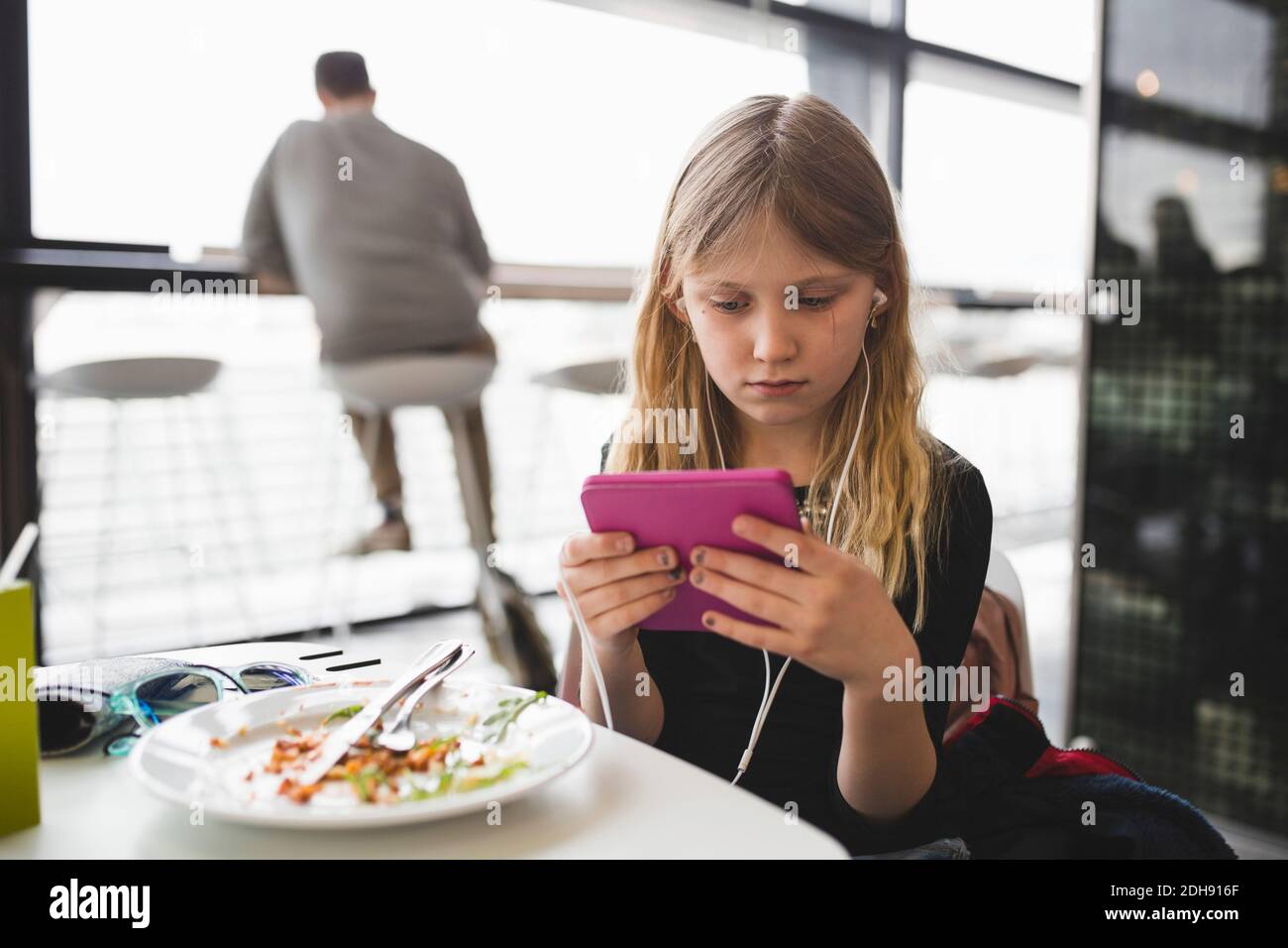 Girl using digital tablet while sitting at table in restaurant Stock Photo