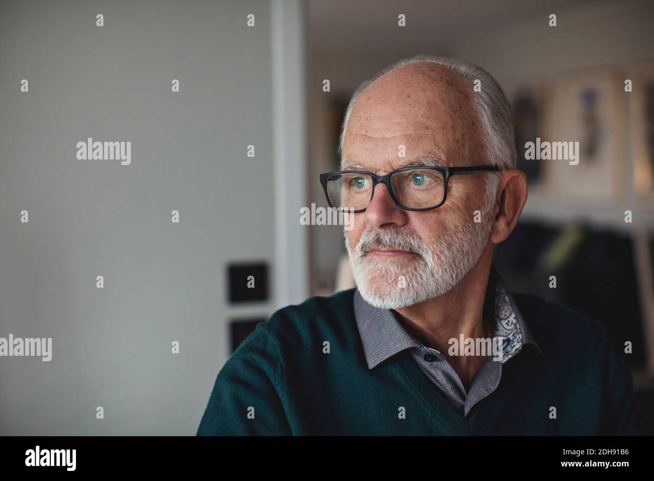 Contemplating senior man wearing eyewear while looking away at home Stock Photo