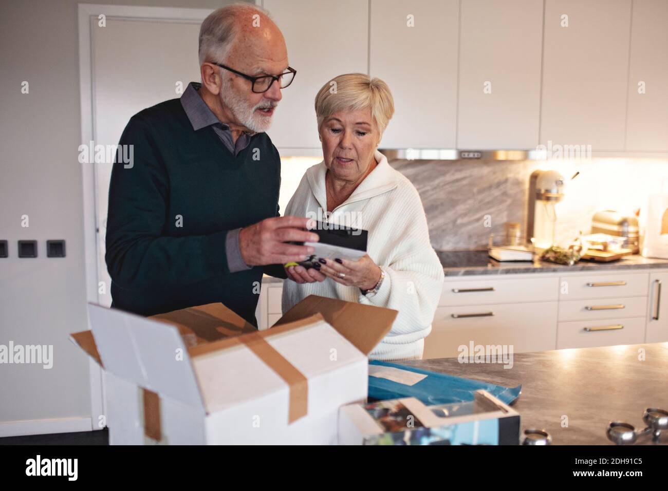 Senior couple unpacking package over kitchen island at home Stock Photo
