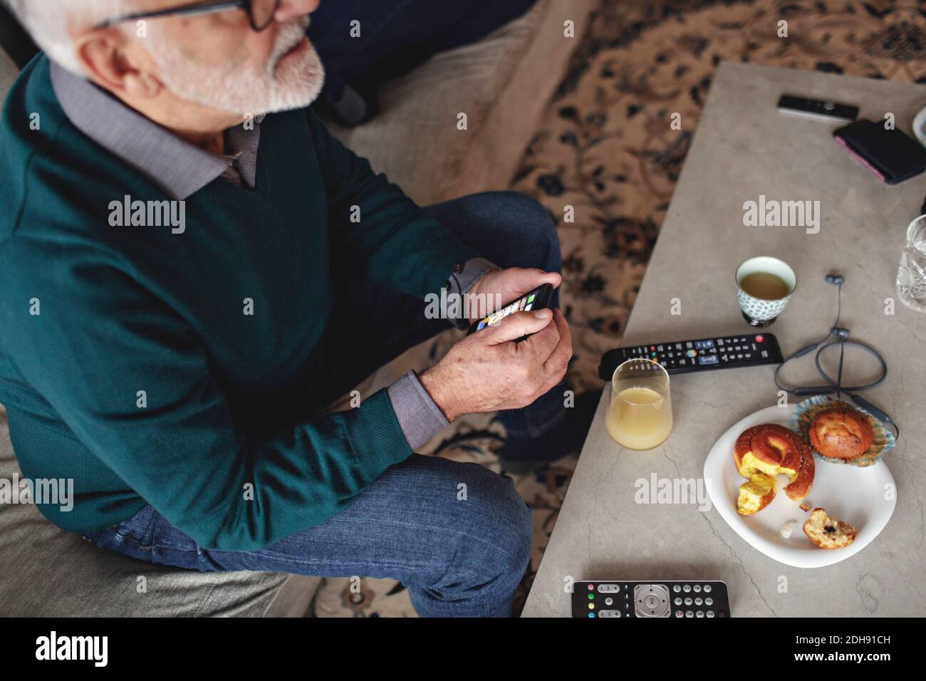 High angle view of senior man with smart phone while sitting on sofa in living room Stock Photo