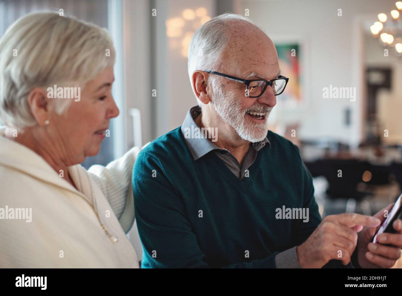 Smiling senior couple using smart phone while sitting in living room Stock Photo