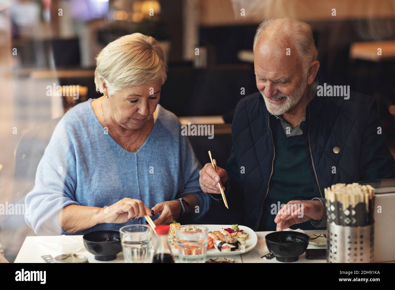 Senior couple eating food while sitting in restaurant Stock Photo