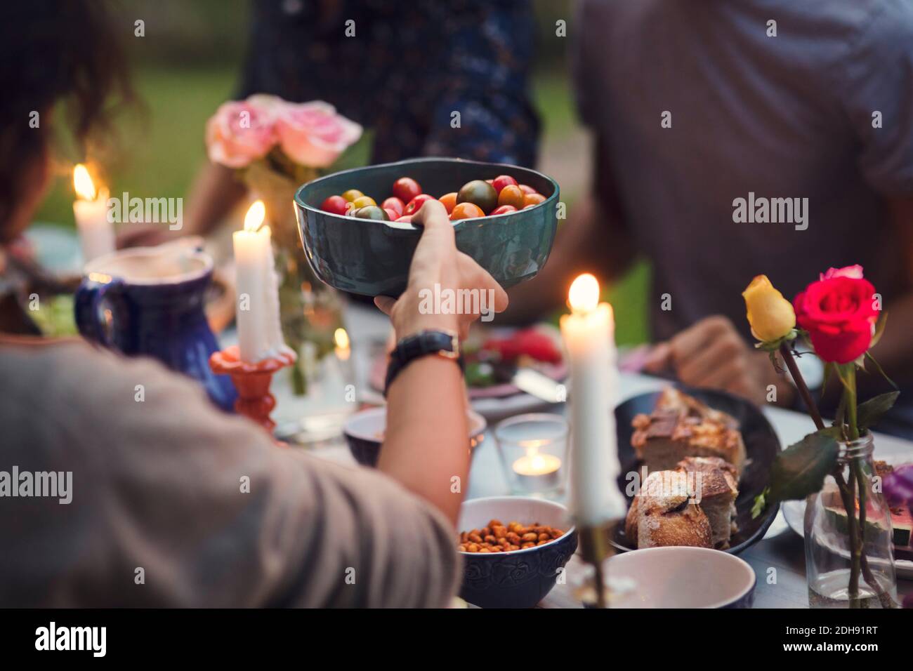 Cropped image of woman serving food to friends at garden party Stock Photo