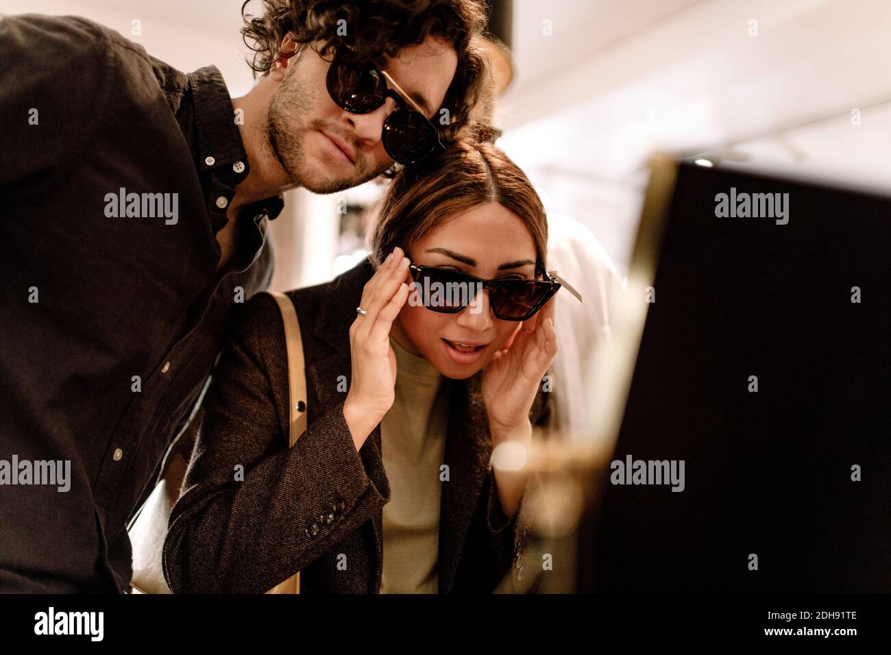 Smiling woman trying fashionable sunglasses with friend at store Stock Photo