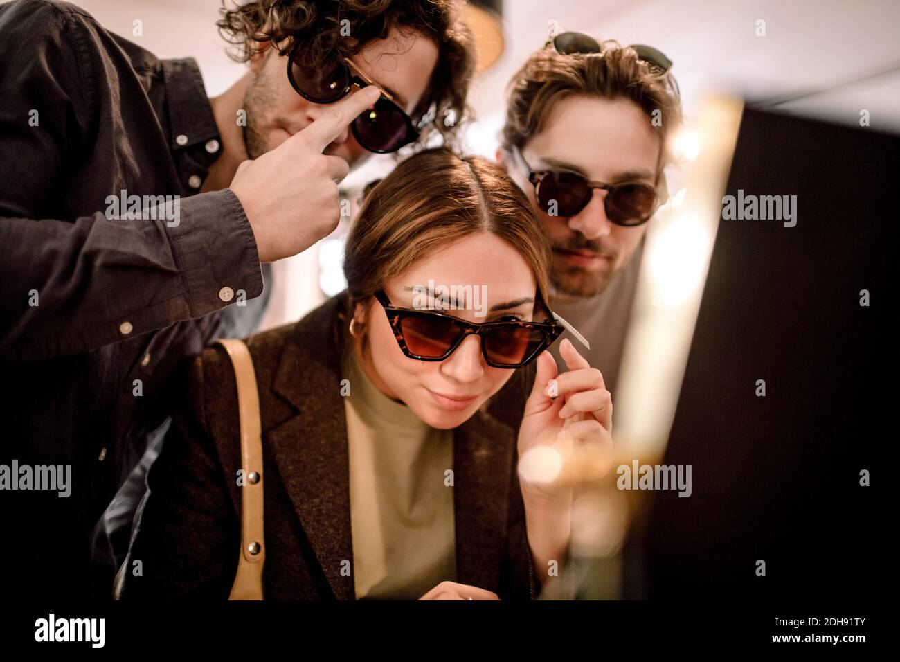 Smiling friends trying fashionable eyeglasses at store Stock Photo