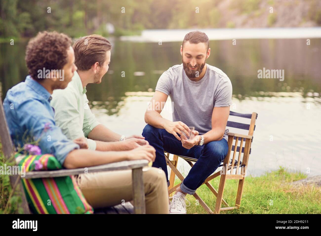 Friends talking while having drink at lakeshore Stock Photo