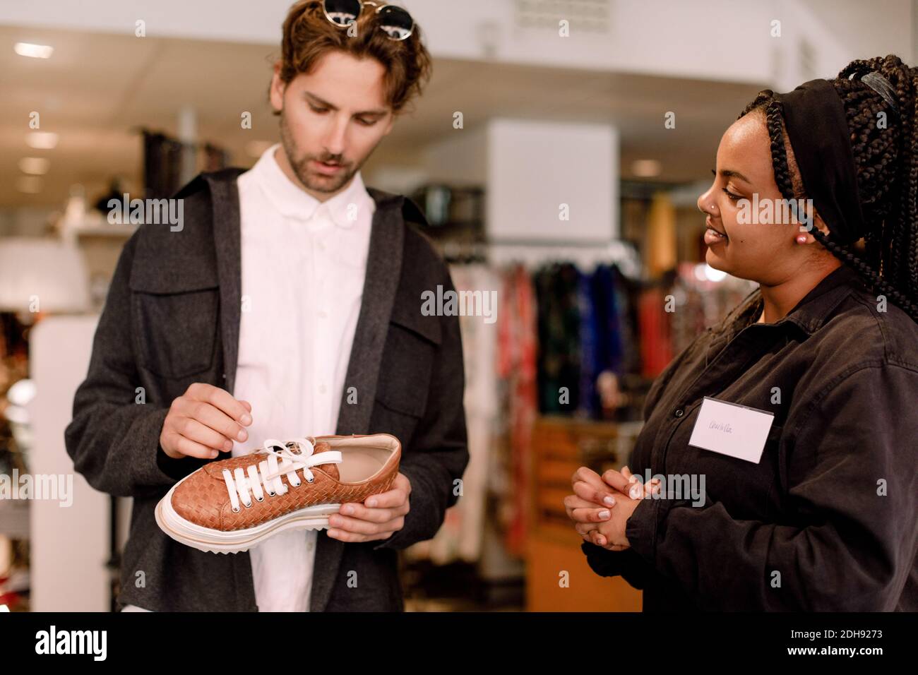 Smiling saleswoman showing shoe to male customer at retail store Stock Photo
