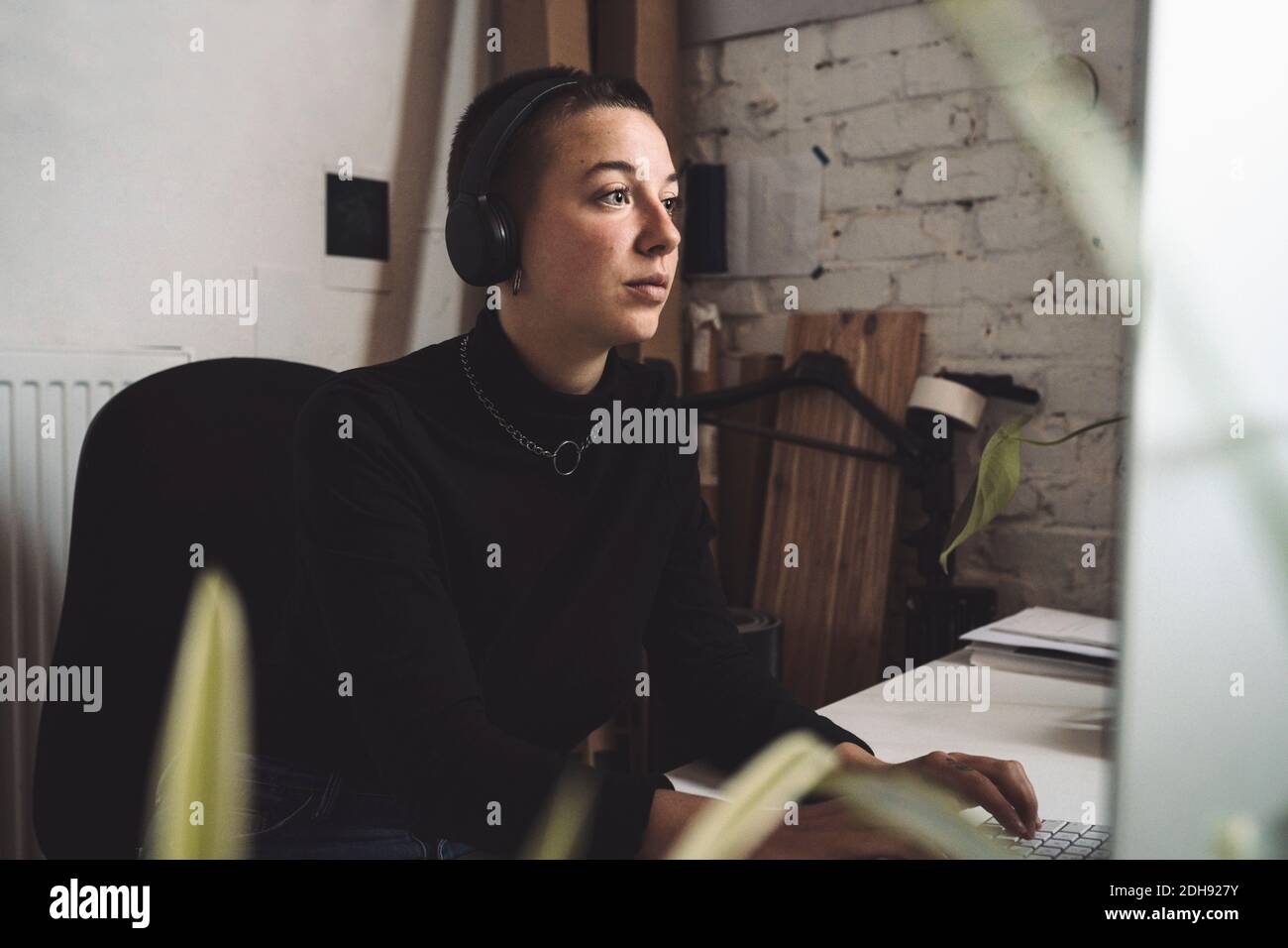 Businesswoman with headphones working on computer at workplace Stock Photo