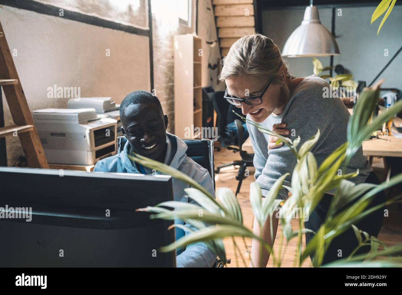 Smiling businessman by colleague working on computer at workplace Stock Photo