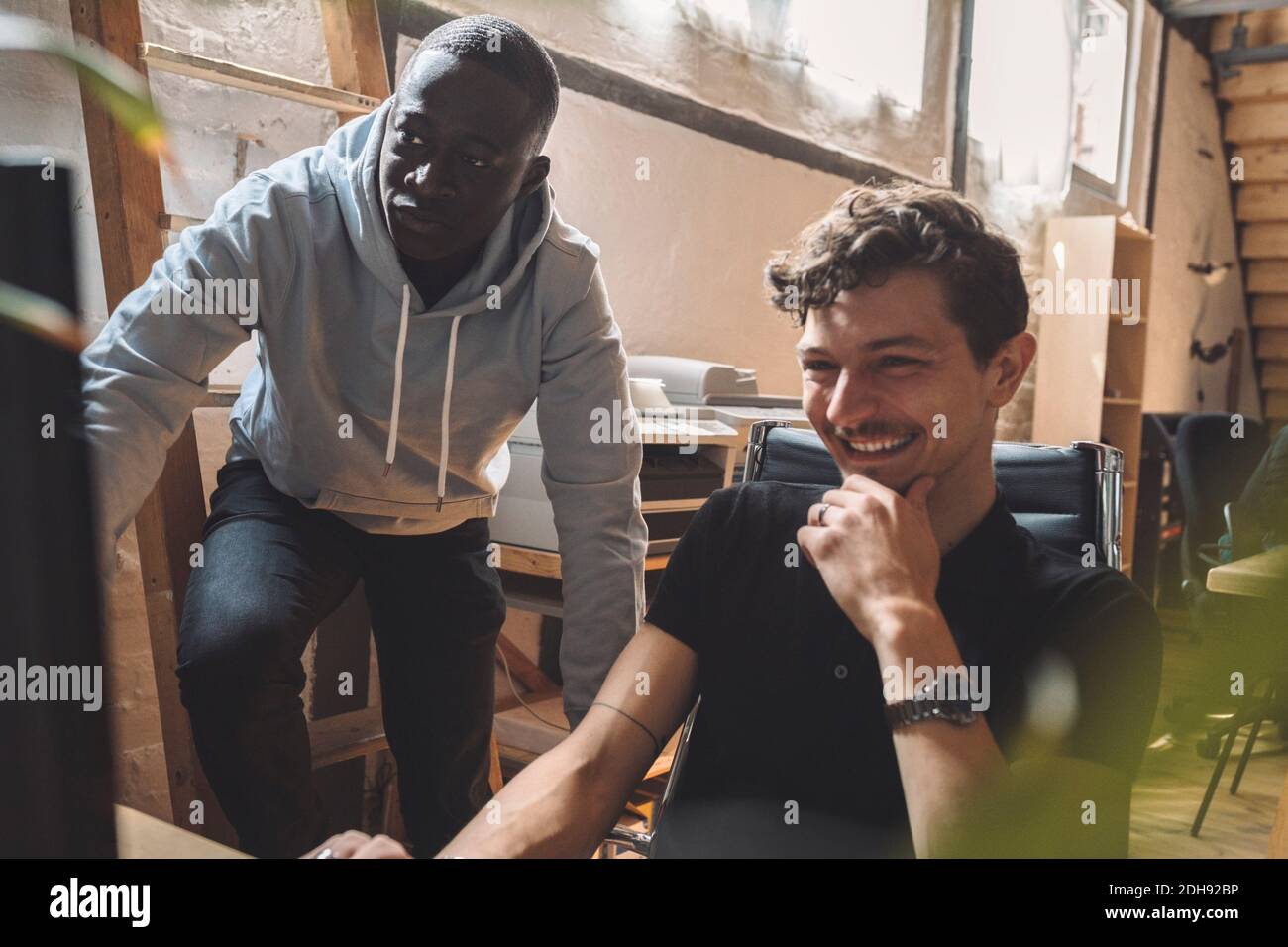 Smiling computer programmer by coworker working on coding at workplace Stock Photo