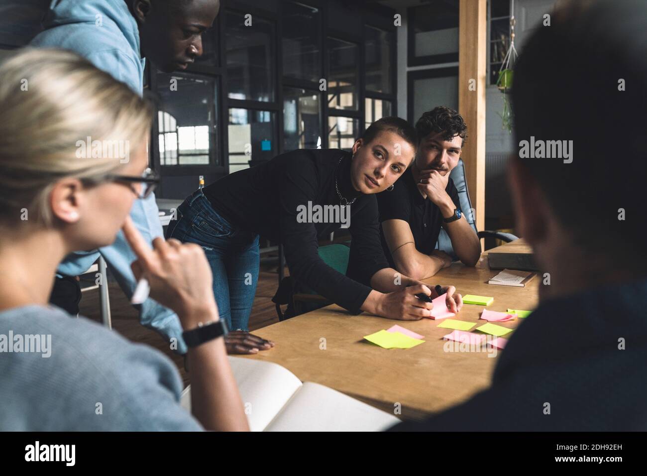 Female freelancer discussing with colleagues over start-up strategy at workplace Stock Photo
