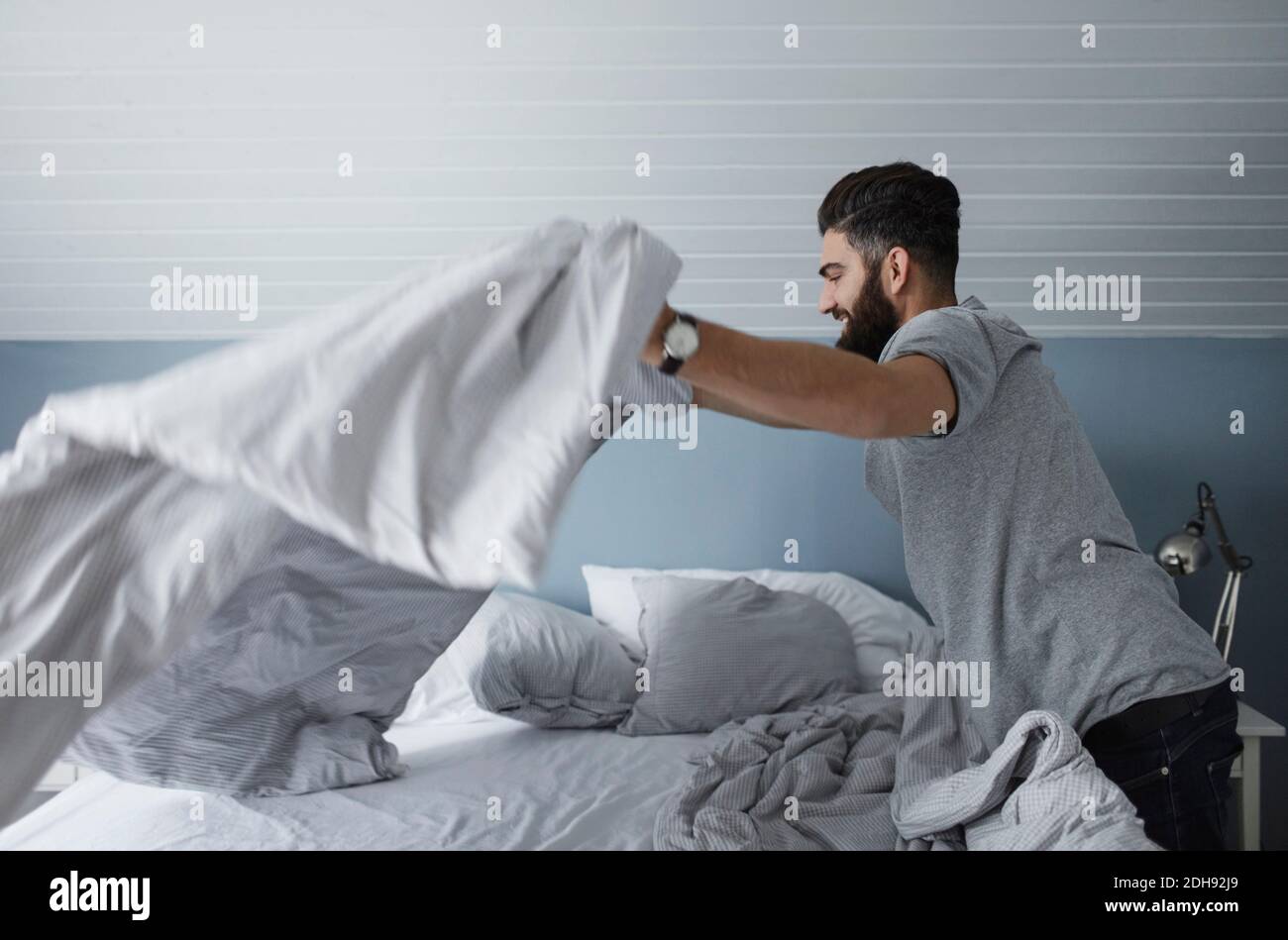 Side view of man making bed at home Stock Photo Alamy
