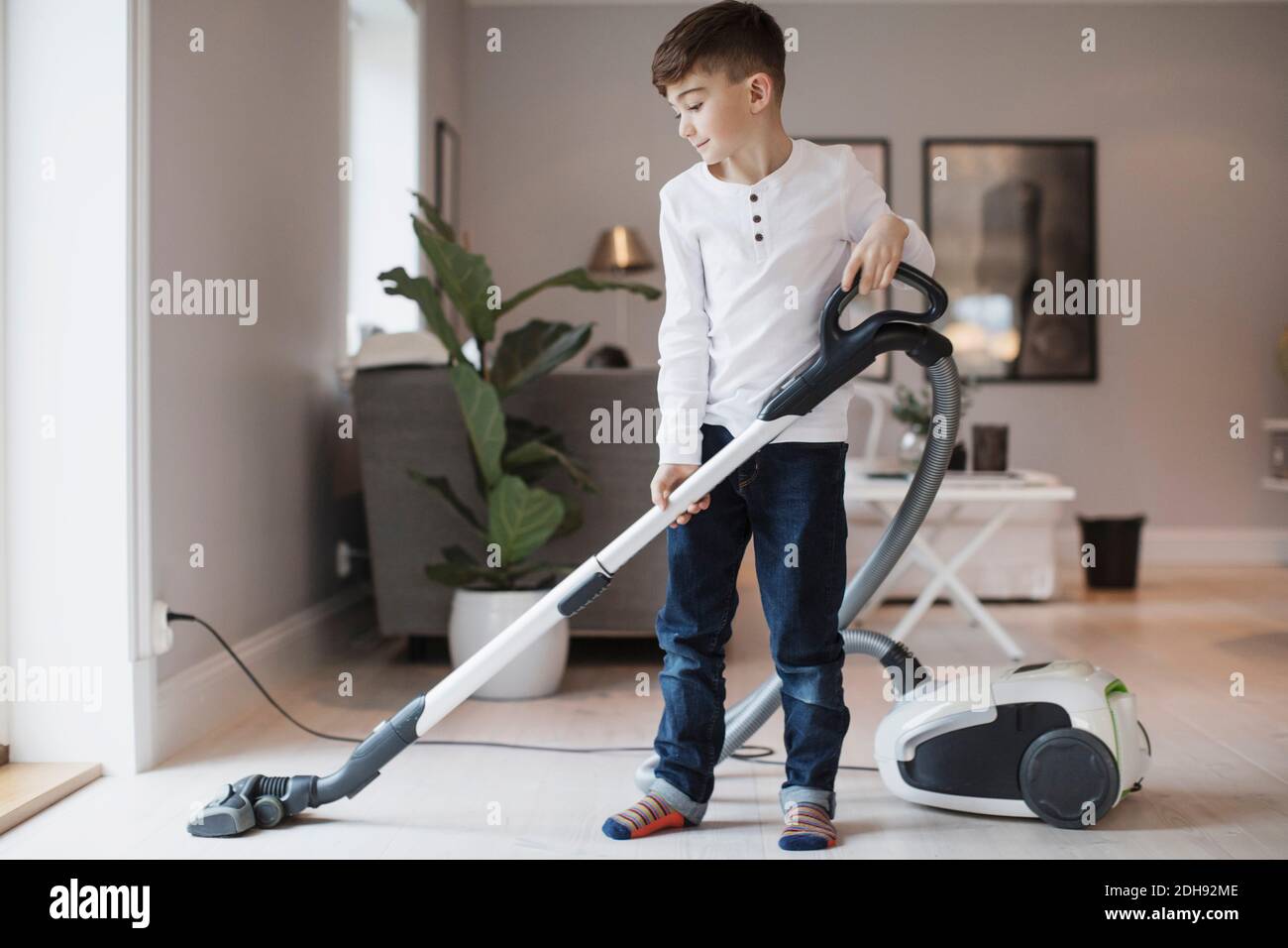 Boy using vacuum cleaner in living room at home Stock Photo Alamy