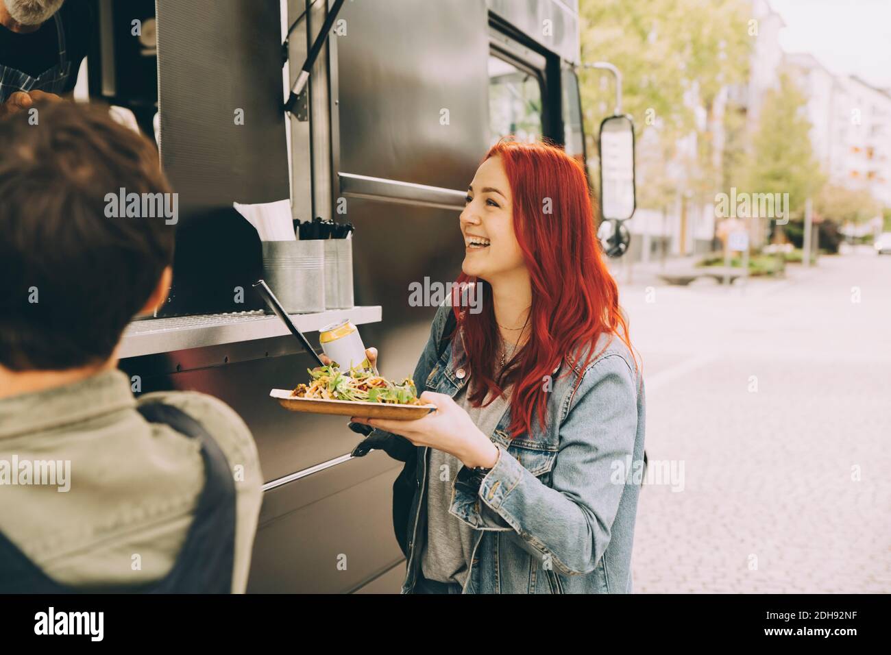 Smiling female customer talking to owner while standing with food plate on street Stock Photo