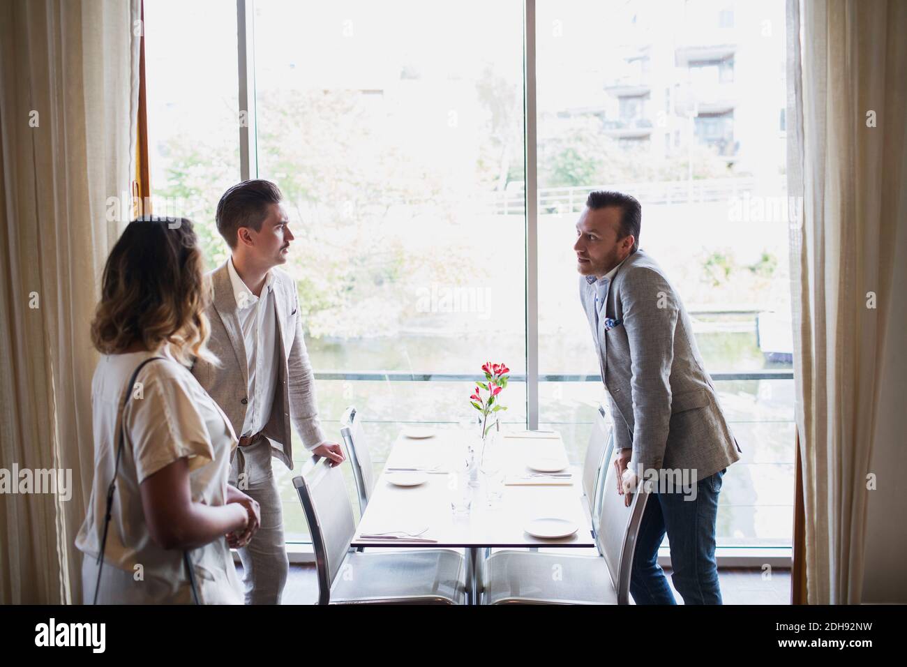 Business people standing by table against window at restaurant Stock Photo