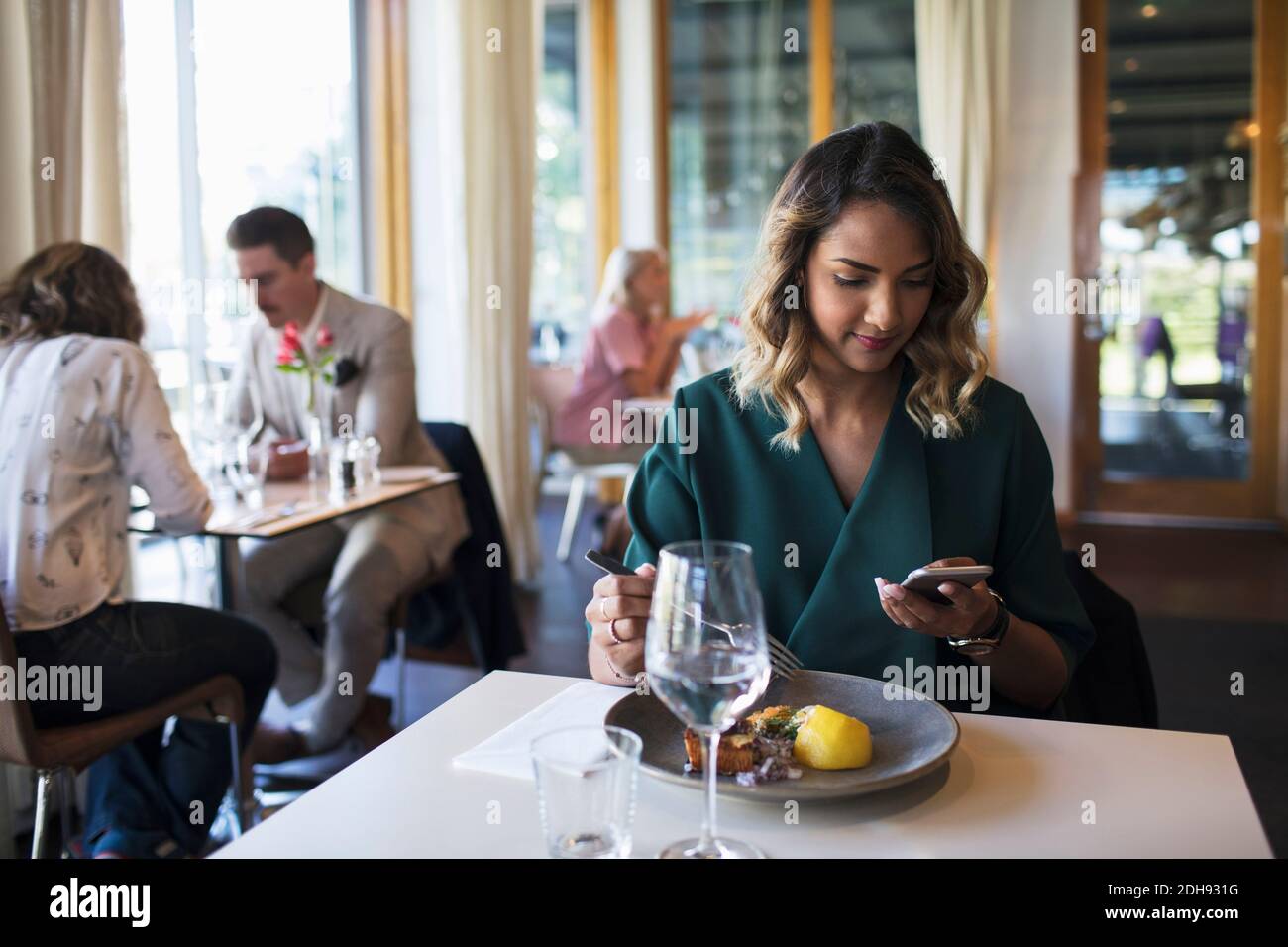 Businesswoman using mobile phone while sitting in restaurant Stock Photo