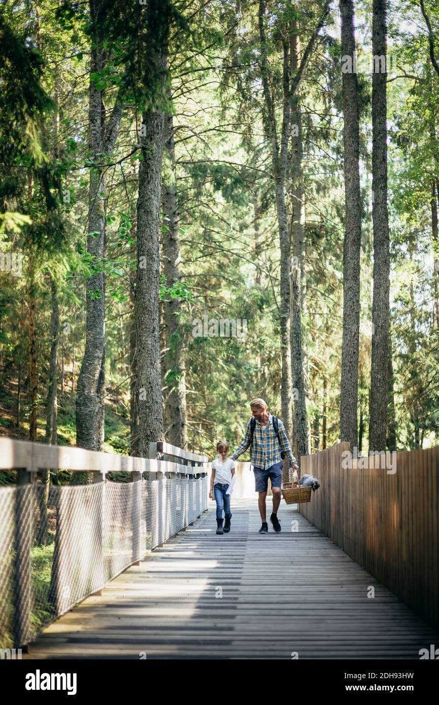 Father talking to daughter while walking on footbridge in forest Stock ...