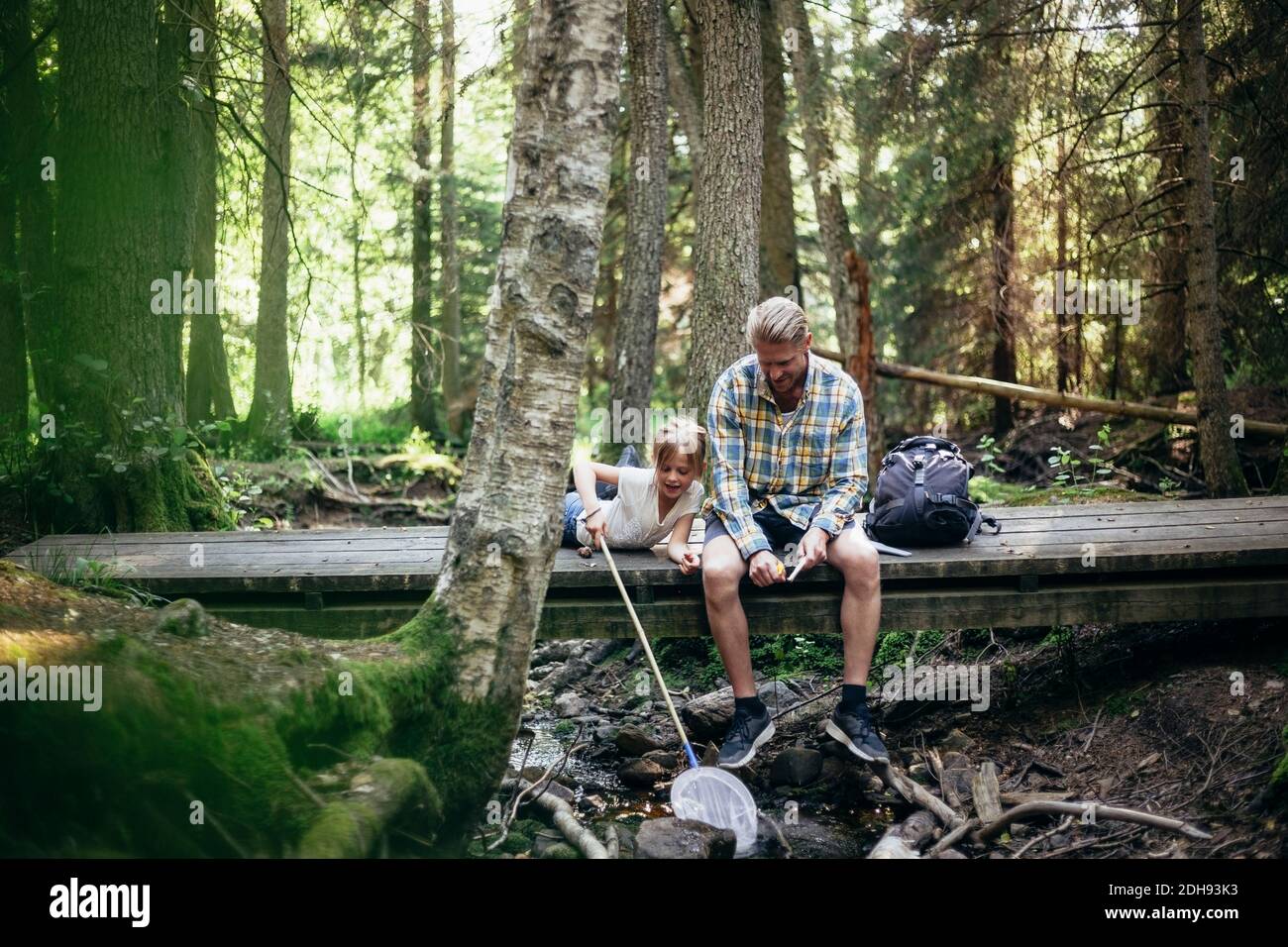 Father with backpack talking to daughter while sitting on footbridge in ...