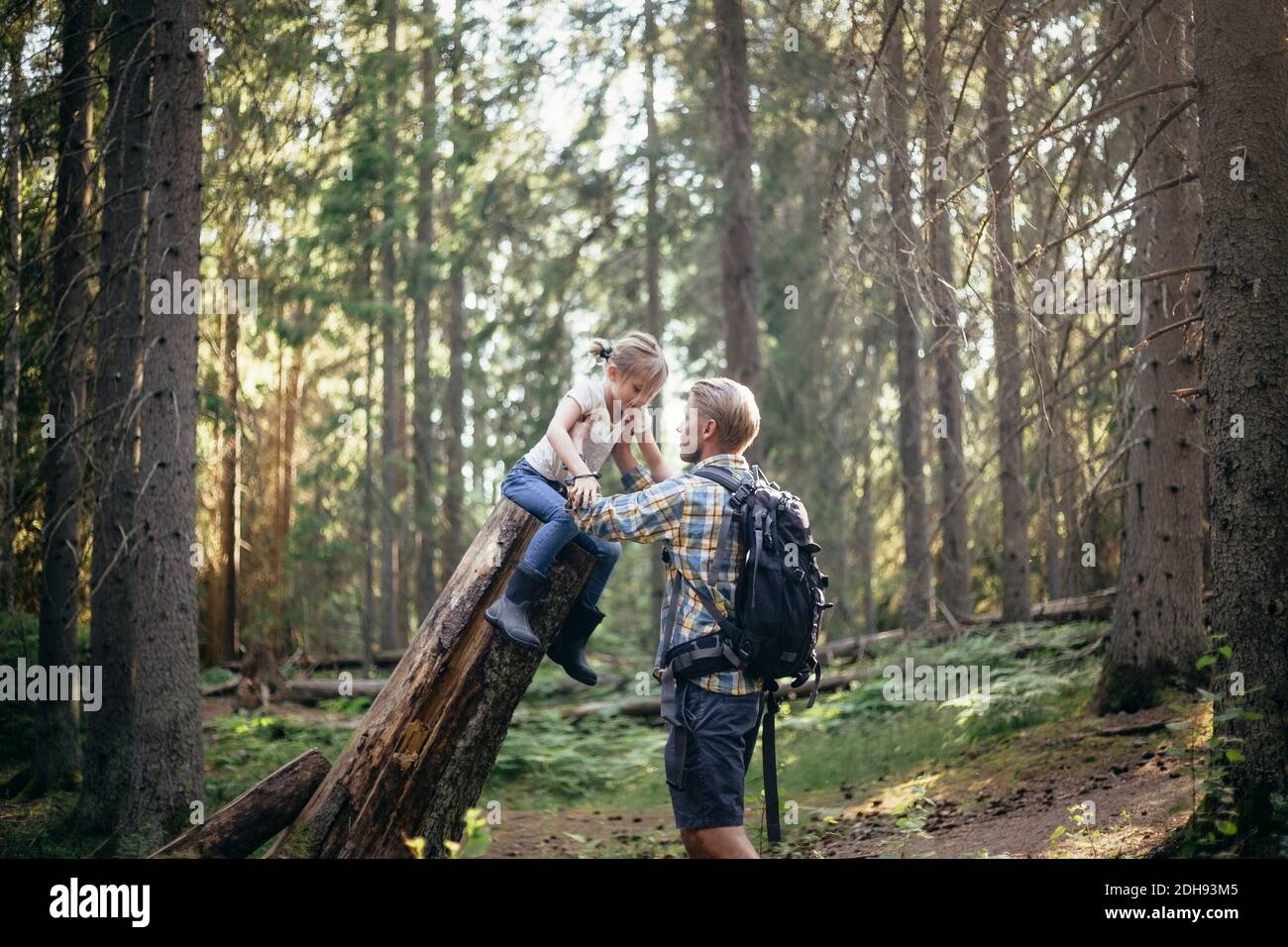 Father holding daughter over log in forest Stock Photo - Alamy