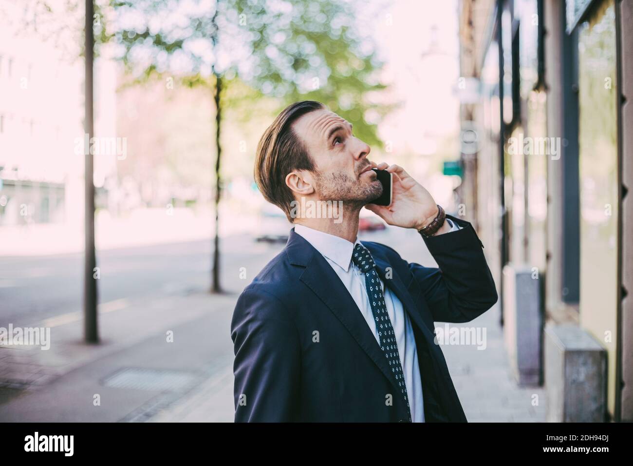 Side view of businessman talking on phone in city Stock Photo