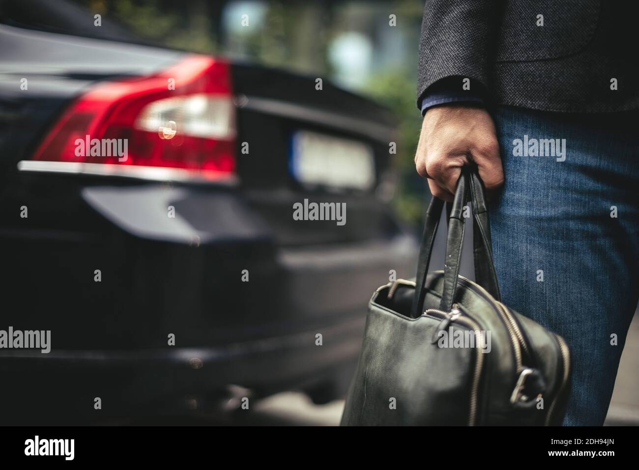 Midsection of businessman carrying briefcase by car Stock Photo