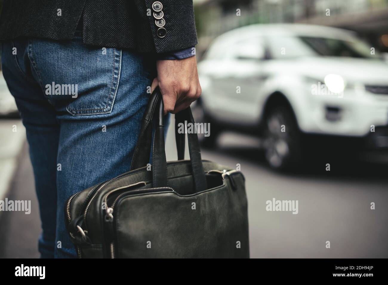 Midsection of businessman carrying briefcase on street Stock Photo