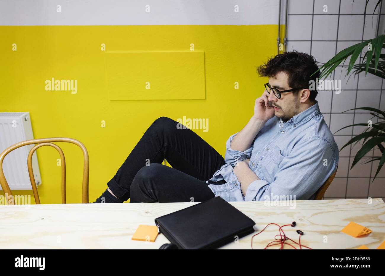 Young man using smart phone while sitting at desk in board room Stock Photo