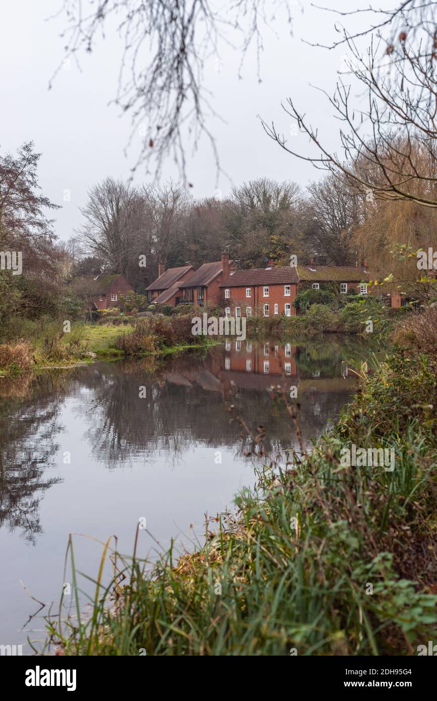River cottages along the Itchen River in Winchester on a murky, grey and misty day during November, Hampshire, England, UK Stock Photo