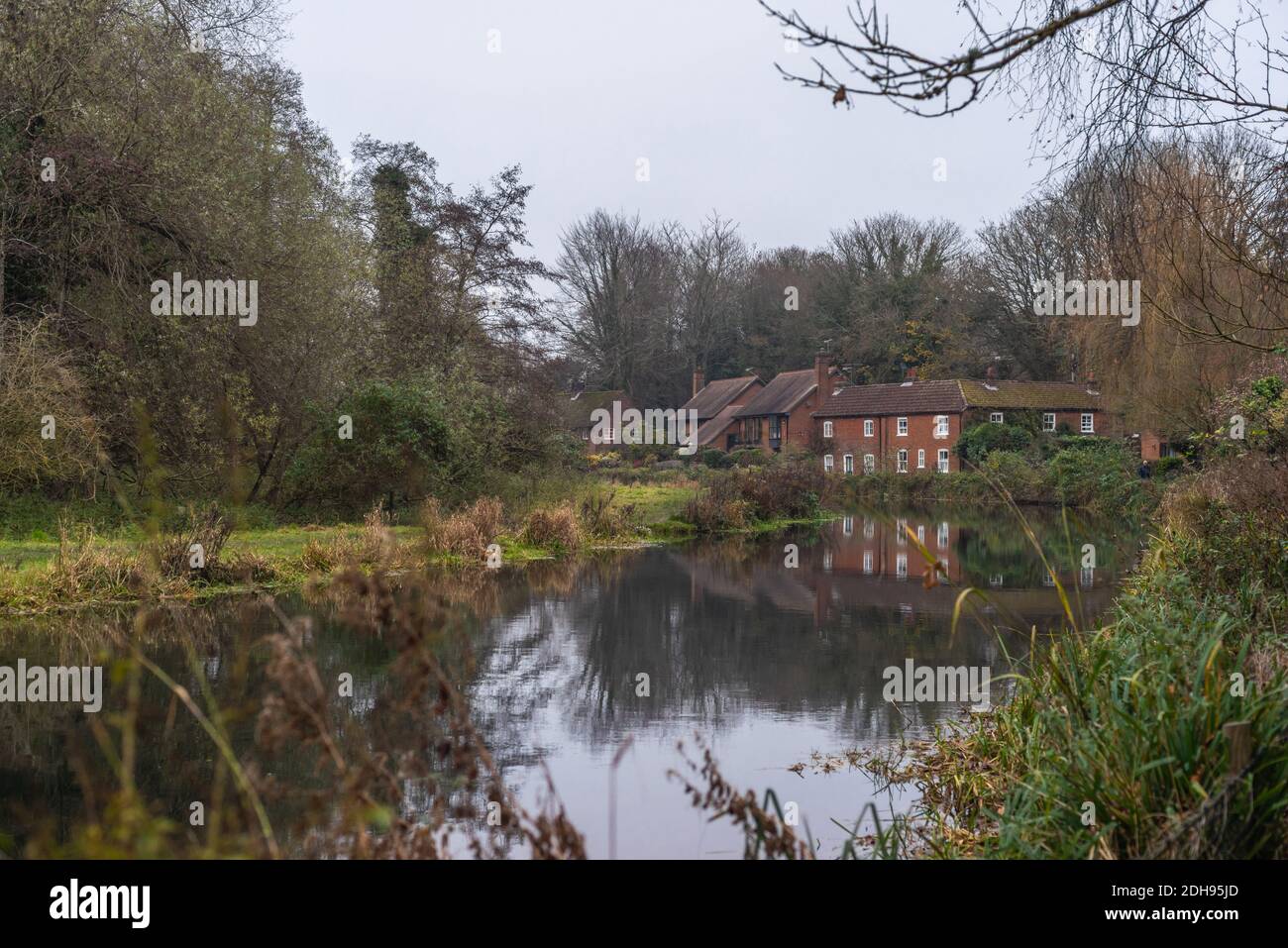 River cottages along the Itchen River in Winchester on a murky, grey and misty day during November, Hampshire, England, UK Stock Photo