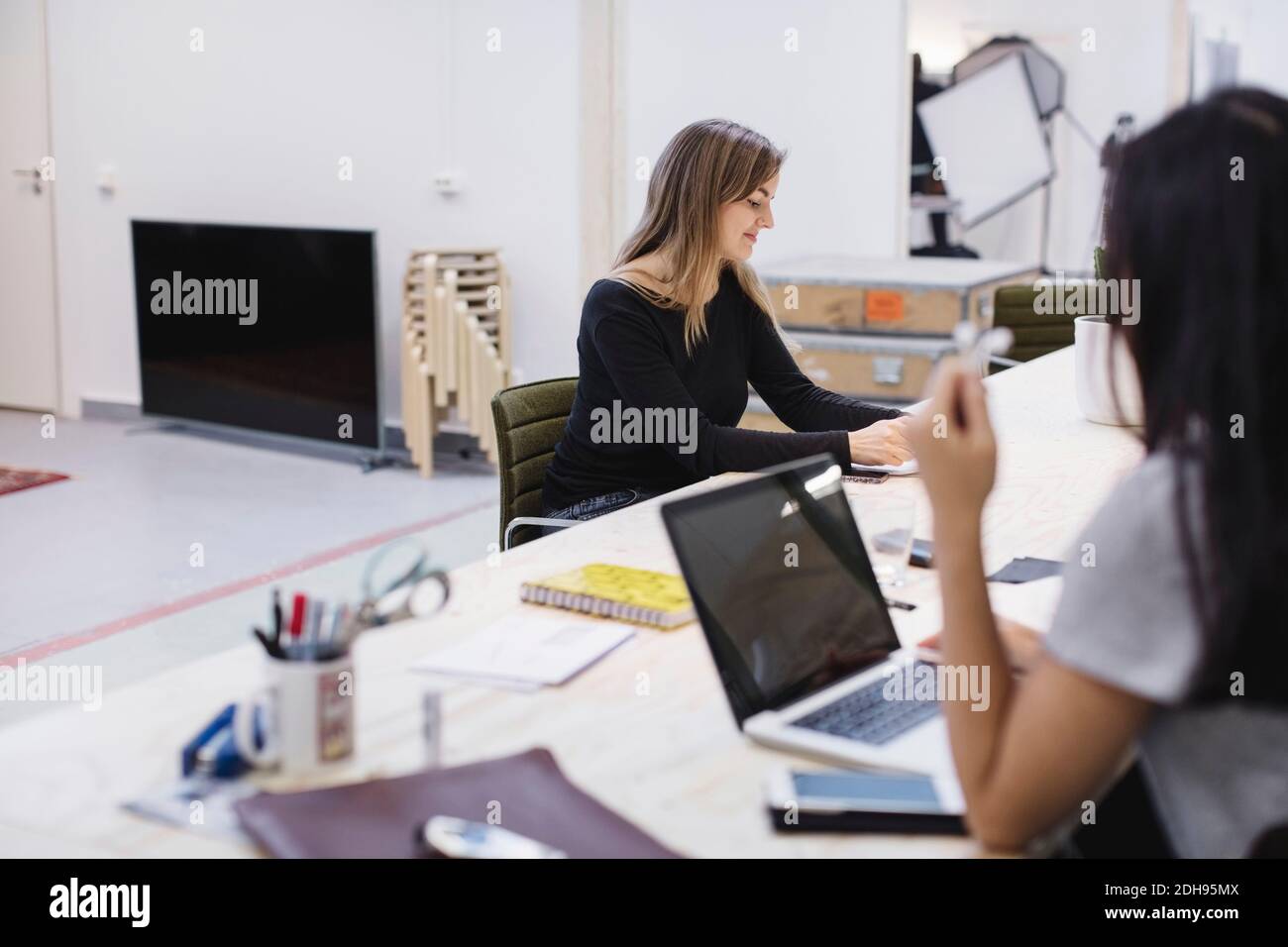 Two young women working at desk in creative office Stock Photo