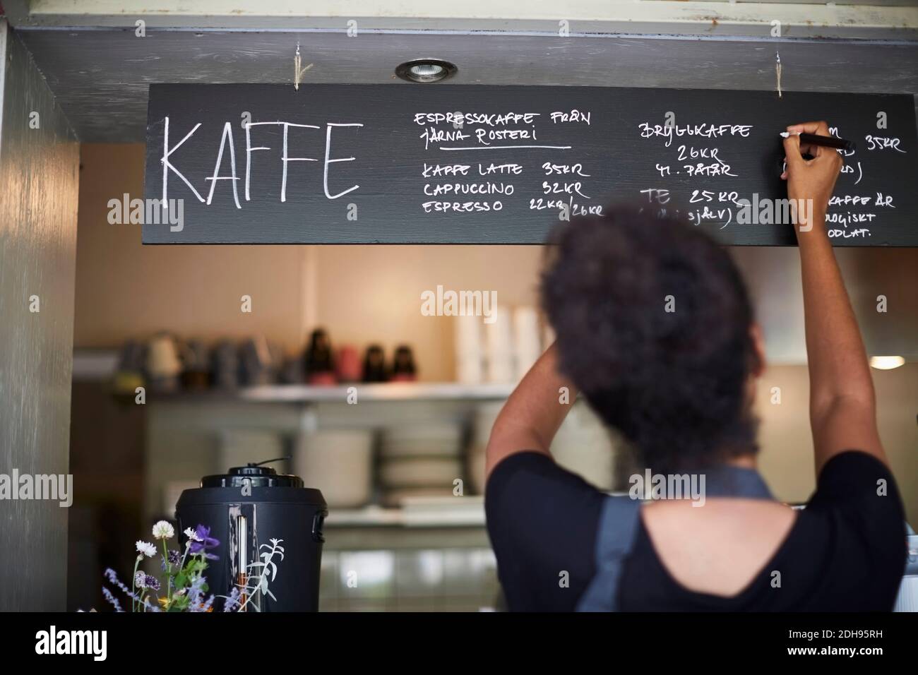 Rear view of waitress writing on blackboard at cafe Stock Photo